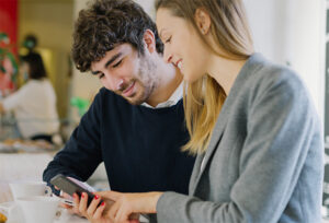 Young couple smiling while looking at a smartphone together.