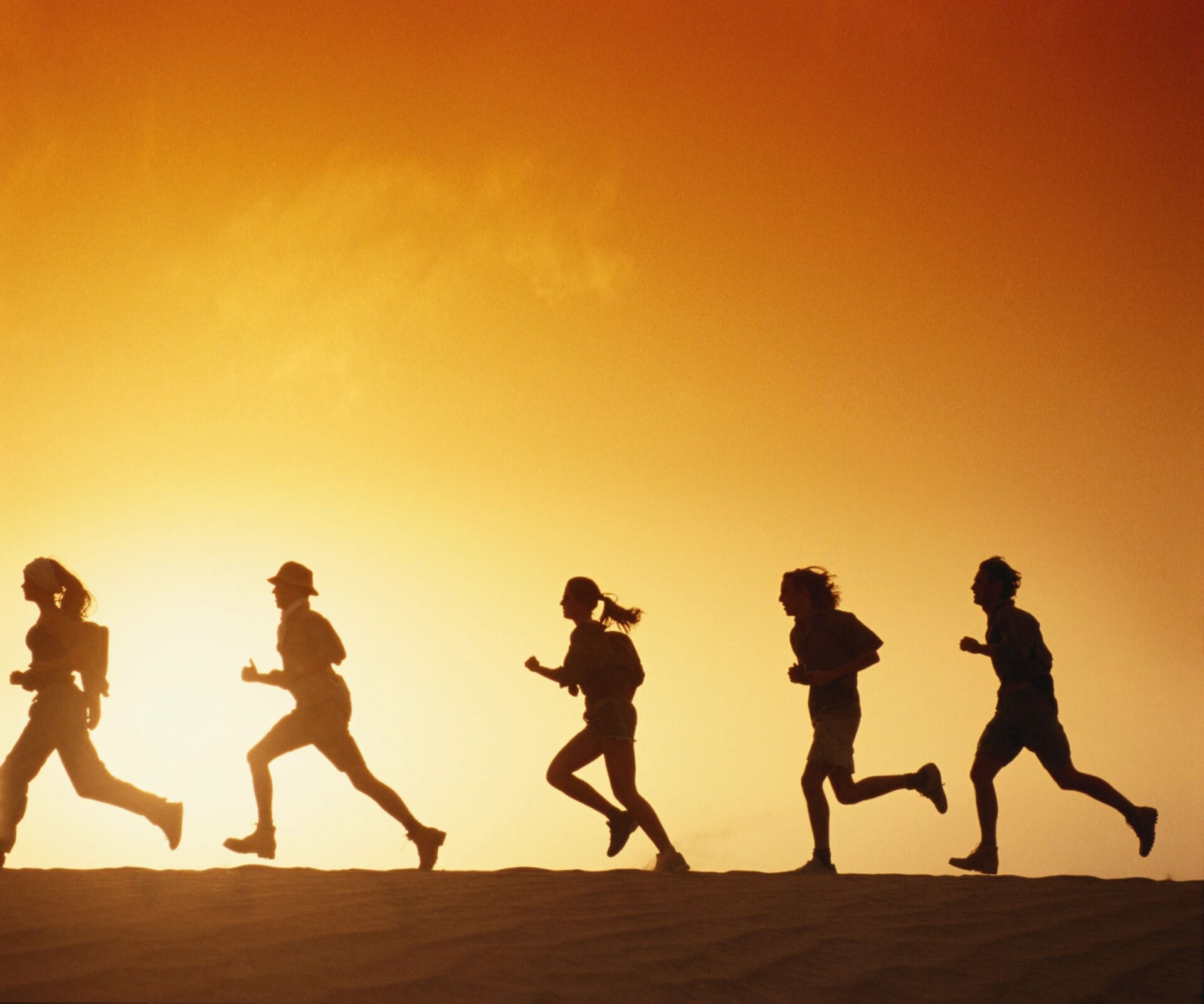 A group of friends running on the sand at the beach