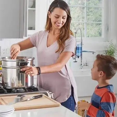 Woman cooking with child watching in a bright kitchen.